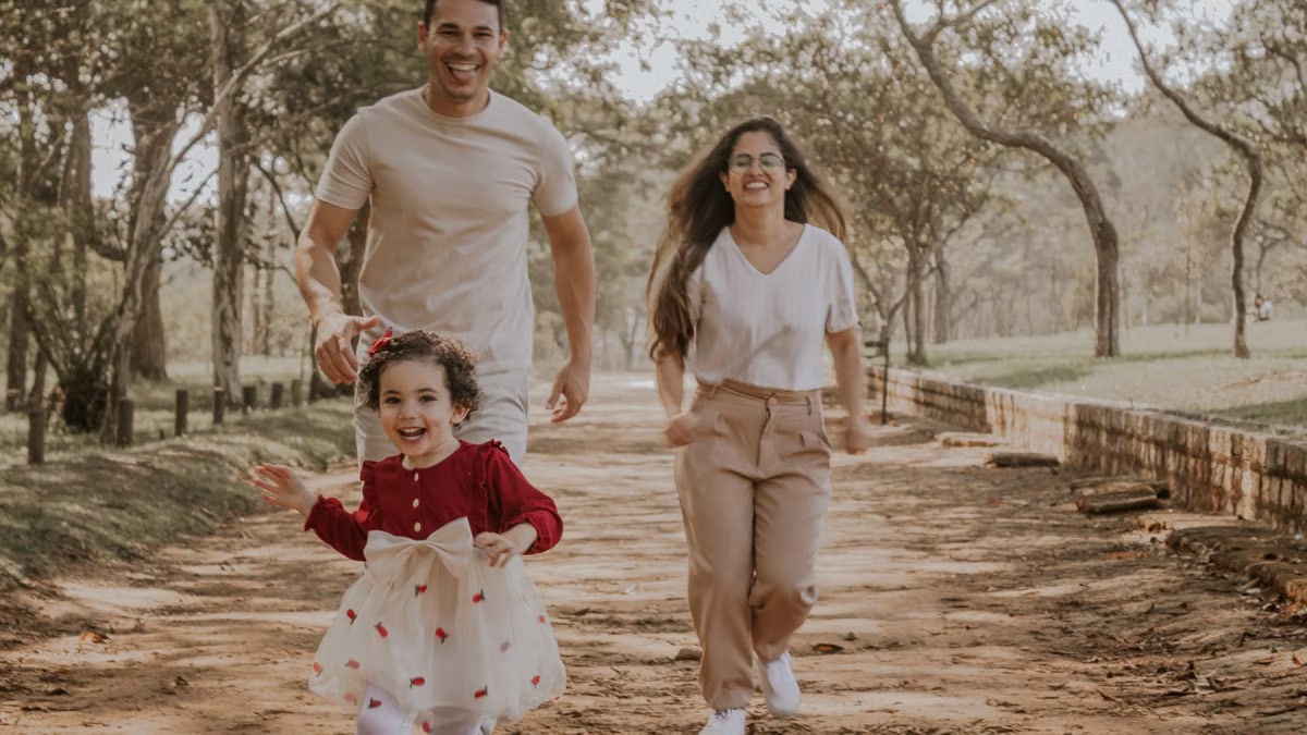 Smiling family enjoys a playful walk in a São Paulo park during a sunny day.
